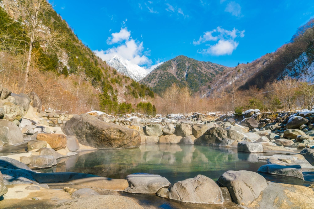 small-pond-surrounded-by-rocks-with-mountain-in-the-background